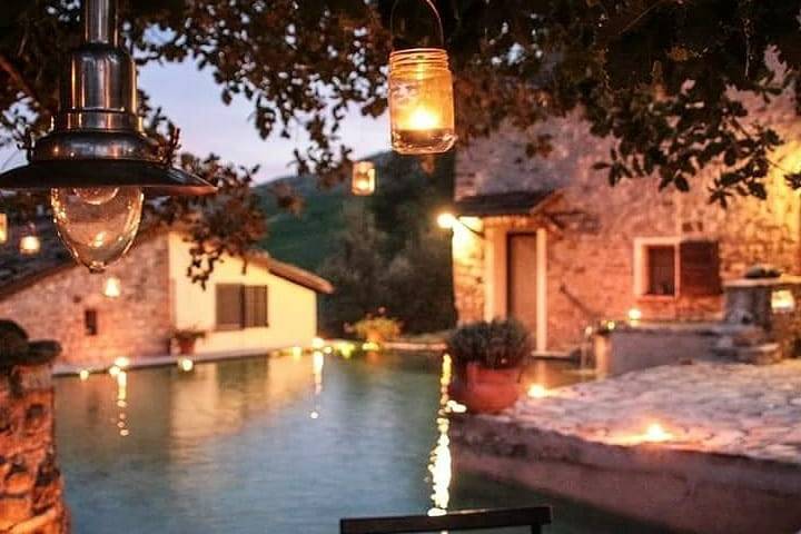 Podere Calvanella al tramonto, con la piscina illuminata dalle lanterne